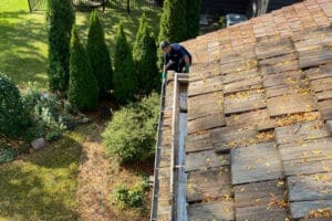 person cleaning house gutters